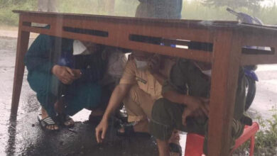 Photo of CSGT và đội trực chốt kiểm dịch nép dưới gầm bàn trú mưa, nhìn xuống đôi dép lại càng thêm xót xa